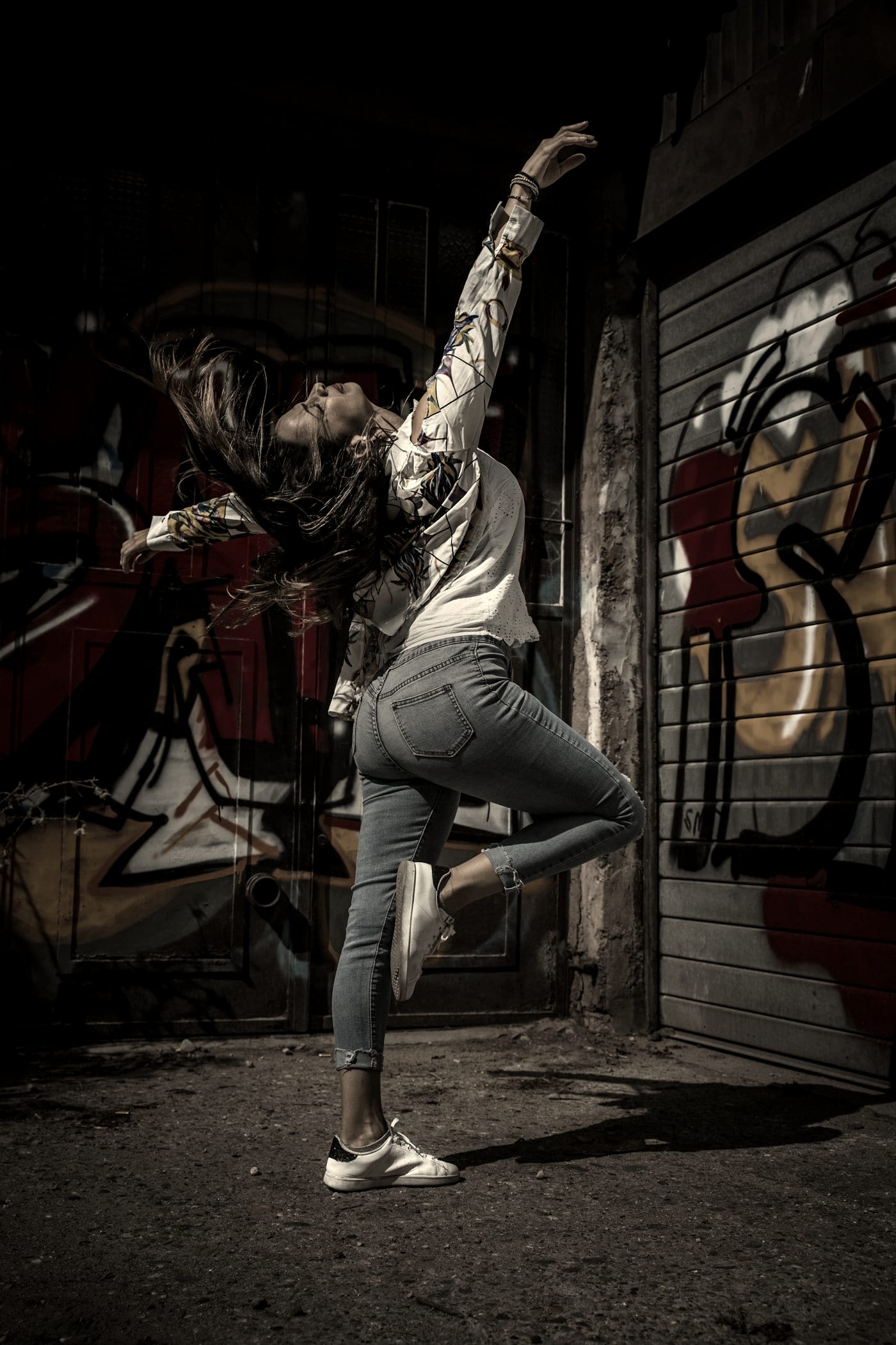 Dancer mid-movement in front of a graffiti wall